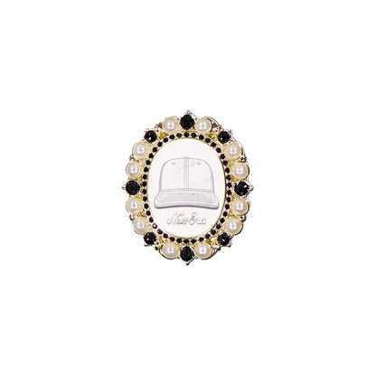 New Era 59FIFTY Day Brooch Black Pin Badge, front view showing an oval design with a stylised cap illustration and embossed New Era logo in the centre, framed by alternating black stones and pearl-like beads.
