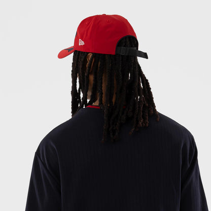 New Era Sultanes De Monterrey LMB Navy Oversized T-Shirt, back view on a model featuring a ribbed neckline in red, worn with a red cap displaying an embroidered New Era logo on the side, showing a relaxed fit and vertical stripes on the navy fabric.