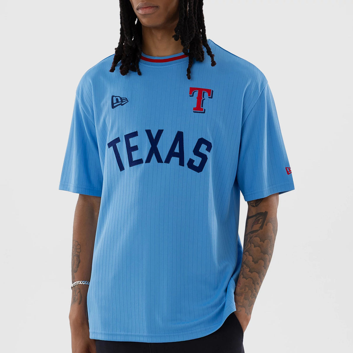 New Era Texas Rangers MLB Pastel Blue Oversized T-Shirt, front view on a model showcasing a pastel blue design with a prominent navy TEXAS across the chest, an embroidered red T logo on the left side, and a New Era logo on the right shoulder.