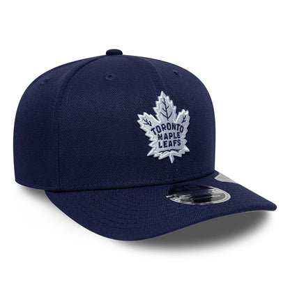 Toronto Maple Leafs NHL Team Navy New Era 9SEVENTY Stretch Snap Adjustable Cap, front view showing the white embroidered maple leaf logo on the navy front panel, navy curved visor, and 9SEVENTY size sticker on the visor.