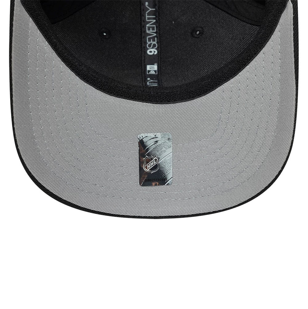 Boston Bruins NHL Team Black New Era 9SEVENTY Stretch Snap Adjustable Cap, inside view showing the grey undervisor with an NHL authenticity sticker, black taping along the seam featuring the 9SEVENTY logo, and a black interior sweatband.
