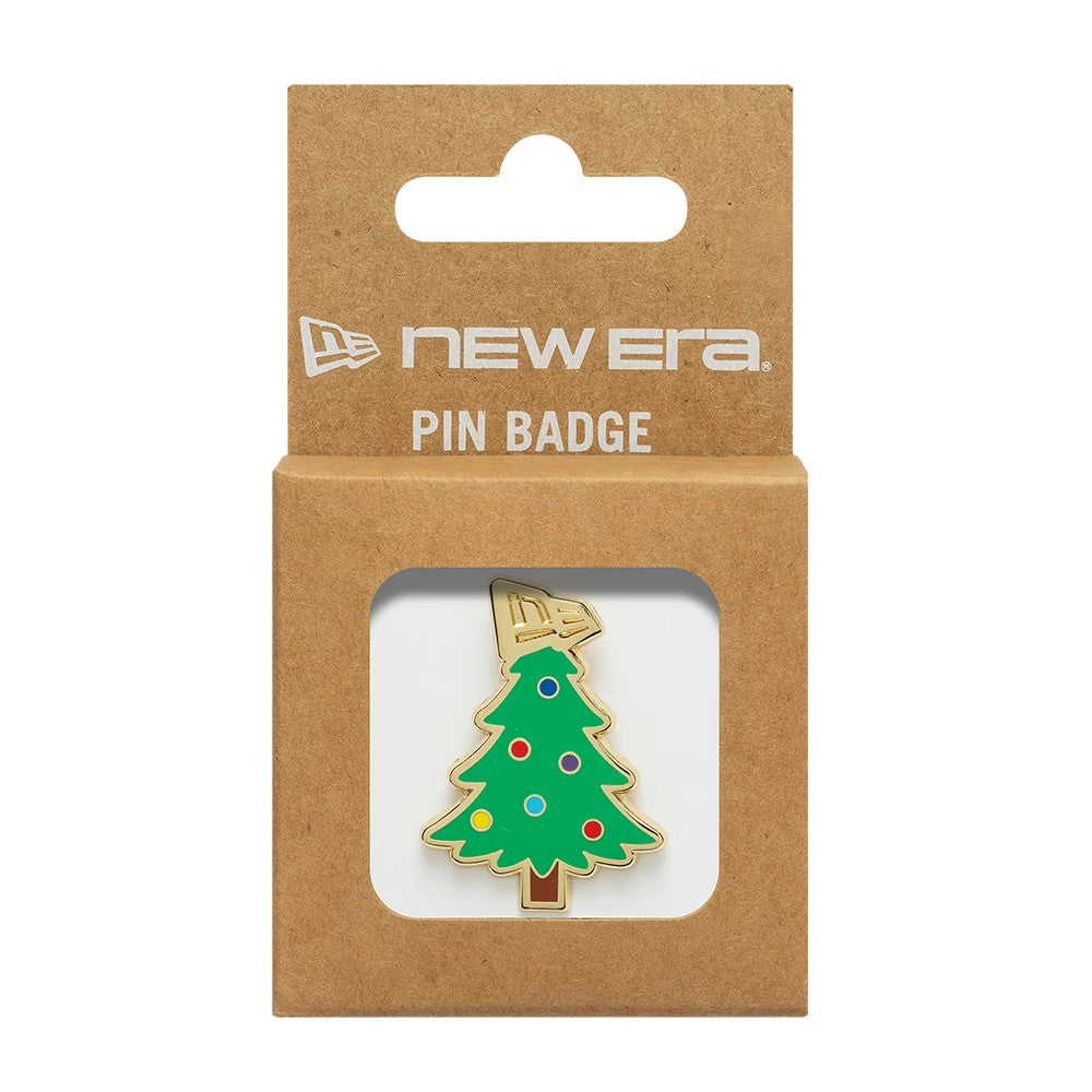 New Era Xmas Tree Open Green Pin Badge, front view showing a festive green Christmas tree design with colourful baubles set against a gold outline, packaged in a brown cardboard box featuring a white printed New Era logo at the top.