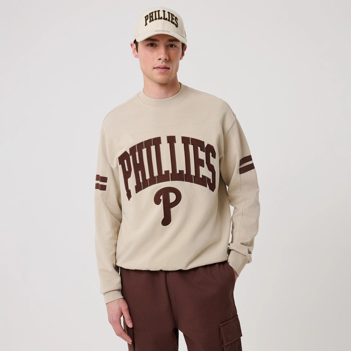 The model is wearing this MLB Arch Graphic Philadelphia Phillies Crew Neck Sweater in light beige. 3