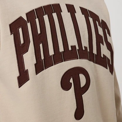 New Era Philadelphia Phillies MLB Arch Graphic Light Beige Crew Neck Sweater, close-up view showing large brown embroidered PHILLIES lettering in an arch design across the chest, with a prominent brown P below on light beige fabric.