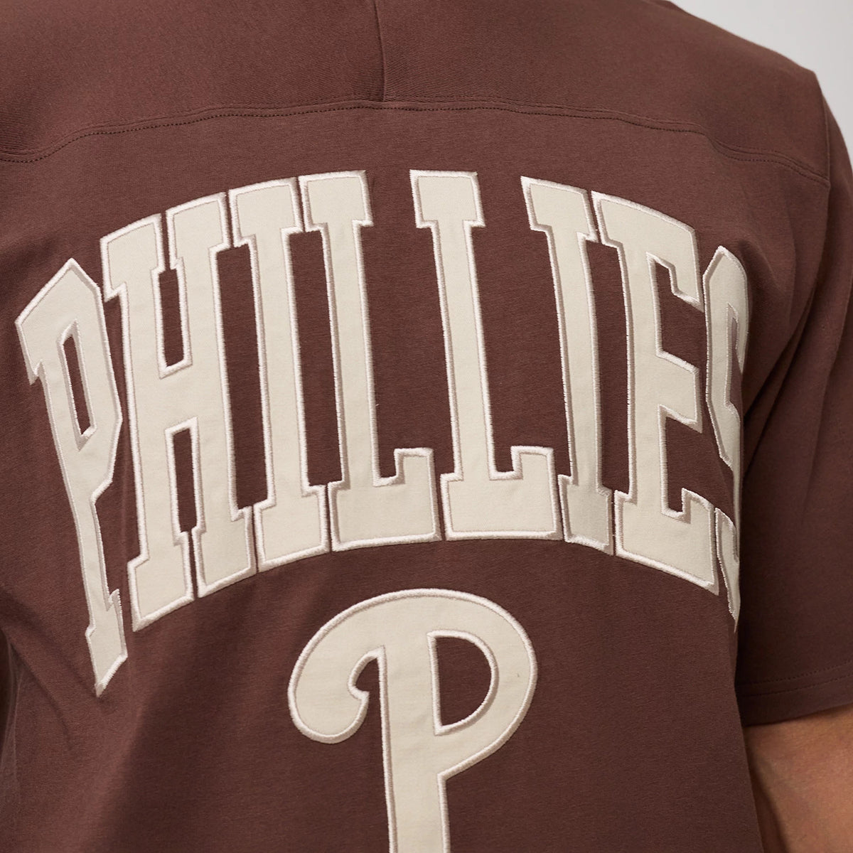 The model is wearing this MLB Arch Graphic Philadelphia Phillies Oversized T-Shirt in brown. 5