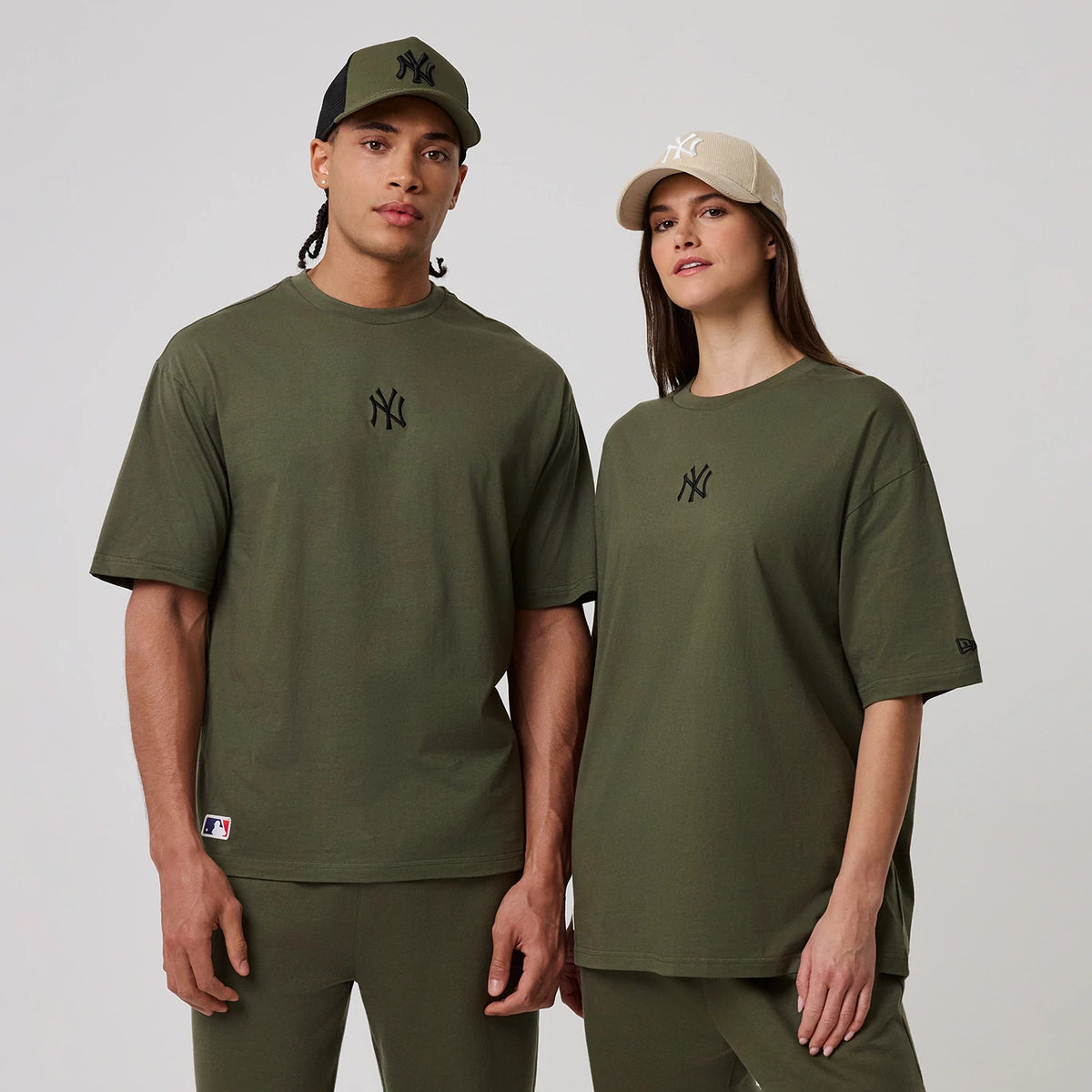 New Era New York Yankees MLB League Essential Green Oversized T-Shirt, front view on two models displaying the dark green oversized fit with the black embroidered NY logo centred on the chest, a New Era logo on the sleeve.