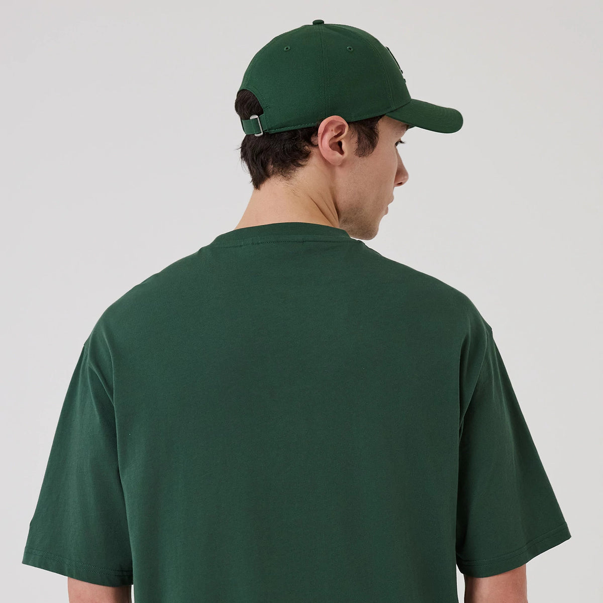 New Era LA Dodgers MLB Food Graphic Dark Green Oversized T-Shirt, back view on a model with a matching dark green cap, showing the plain dark green back with short sleeves and a relaxed fit, no graphics or logos.