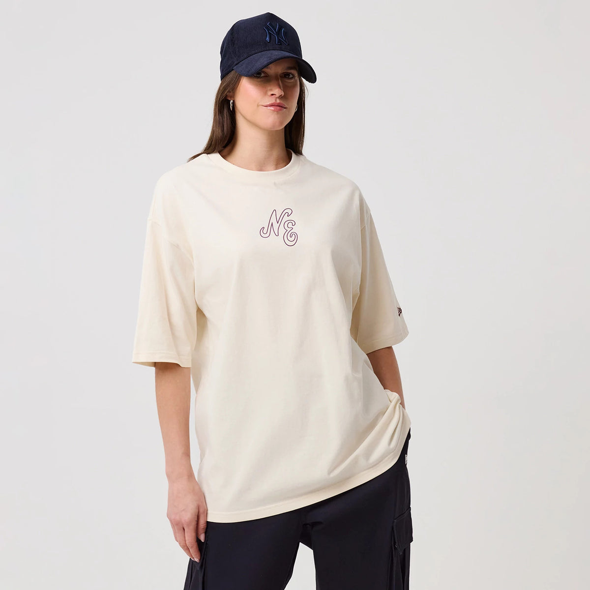 The model is wearing this New Era Crest Graphic Oversized T-Shirt in open white. 4