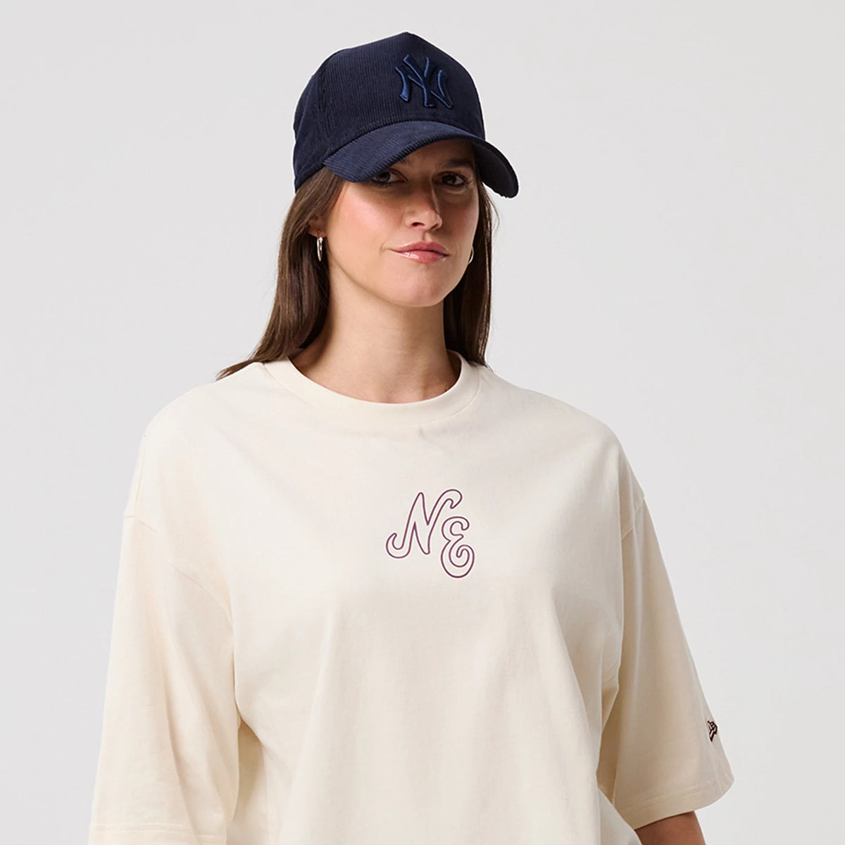 The model is wearing this New Era Crest Graphic Oversized T-Shirt in open white. 6