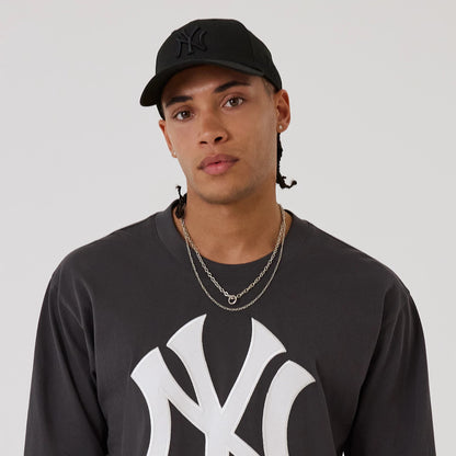 The model is wearing this MLB League Essential New York Yankees Oversized Jersey in charcoal. 6