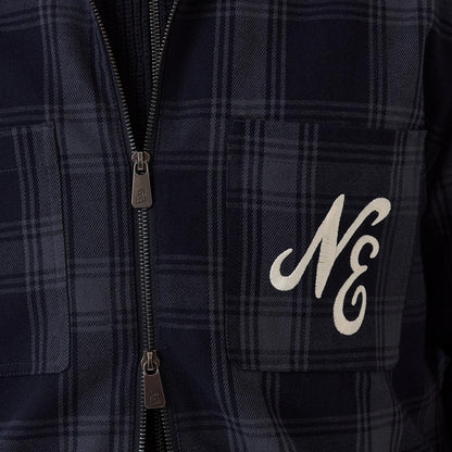 New Era Navy Shacket, front view showing a navy plaid pattern with twin chest pockets, each featuring a zip closure, and a white embroidered NE on the right pocket, highlighting the shacket's casual and versatile style.