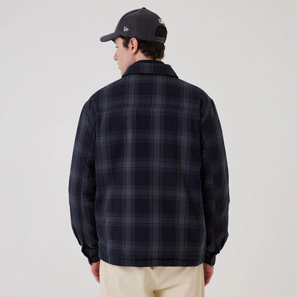 New Era Navy Shacket, back view on a model wearing a grey cap, showcasing the dark navy and grey plaid pattern across the entire surface of the shacket, structured collar, and relaxed fit over beige trousers.
