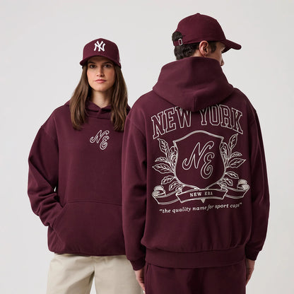 The model is wearing this New Era Crest Graphic Pullover Hoodie in dark purple. 1