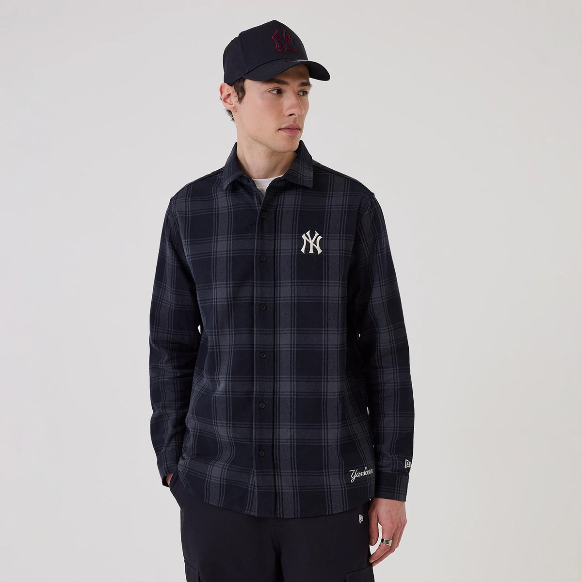 New Era New York Yankees MLB Plaid Navy Long Sleeve Shirt, front view on a model showing the embroidered NY logo on the left chest, a plaid pattern across the fabric, and the New Era flag logo on the left cuff.