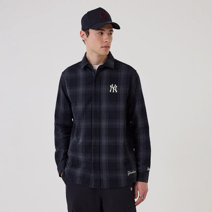 New Era New York Yankees MLB Plaid Navy Long Sleeve Shirt, front view on a model showing the embroidered NY logo on the left chest, a plaid pattern across the fabric, and the New Era flag logo on the left cuff.