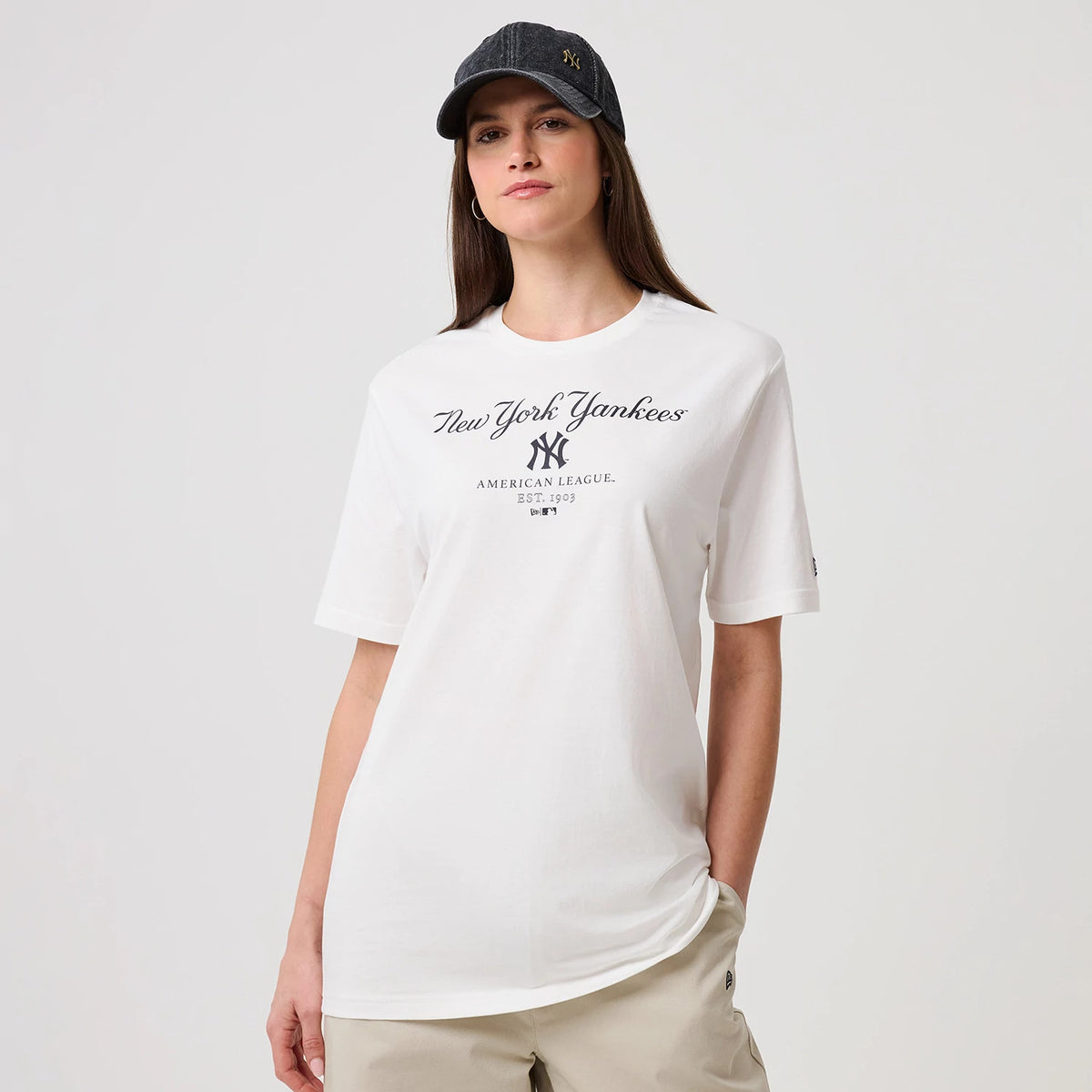 New Era New York Yankees MLB Linear White T-Shirt, front view on a model wearing a dark cap, displaying the printed New York Yankees script logo across the chest, with additional text the American League and establishment year below.