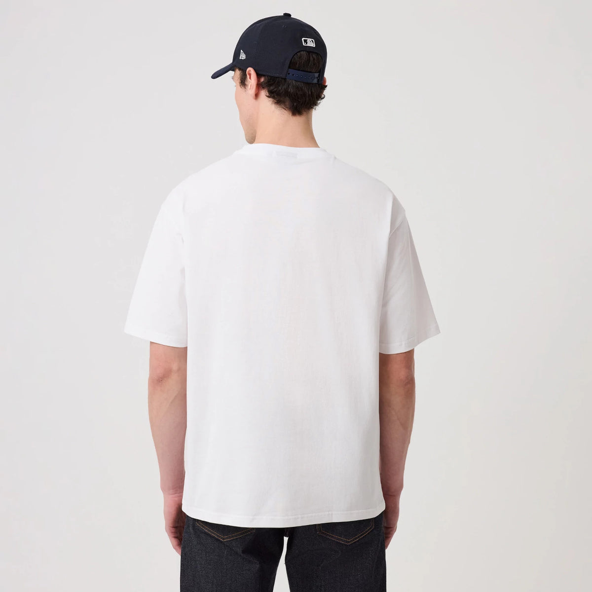 The model is wearing this New Era Heritage Oversized T-Shirt in white. 2