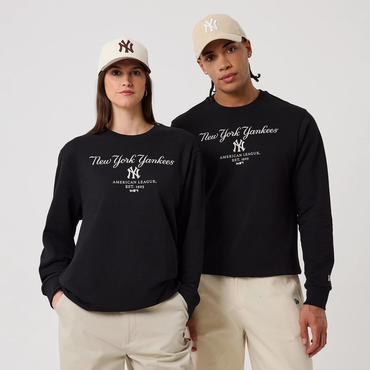 New Era New York Yankees MLB Linear Black Crew Neck Sweater, front view on a model pairing with a beige cap, featuring the script New York Yankees in white, the NY logo and American League Est. 1903 printed across the chest.