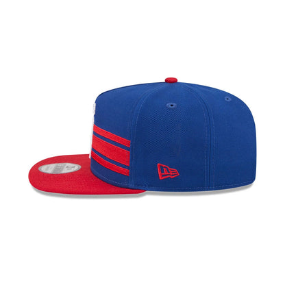 NBA Logo NBA Tip Off 2026 Blue New Era 9FIFTY A-Frame Snapback Adjustable Cap, side view showing raised red New Era flag logo on the left side, red flat visor with 9FIFTY size sticker, and red and blue striped detail.