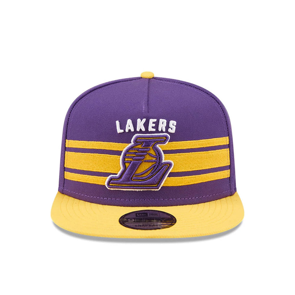 LA Lakers NBA Tip Off 2026 Purple New Era 9FIFTY A-Frame Snapback Adjustable Cap, front view showing raised yellow Lakers logo below white text on purple crown, with two yellow horizontal stripes and a contrasting yellow visor.