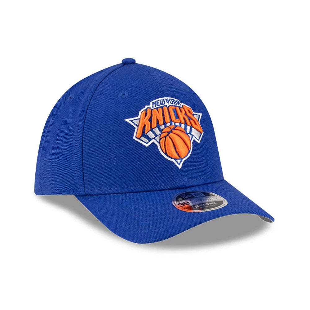 New York Knicks NBA Team Blue New Era 39THIRTY M-Crown Stretch Fit Cap, three-quarter view showing the orange and white embroidered Knicks logo on the structured blue front panel, with a 39THIRTY size sticker on the curved blue visor.