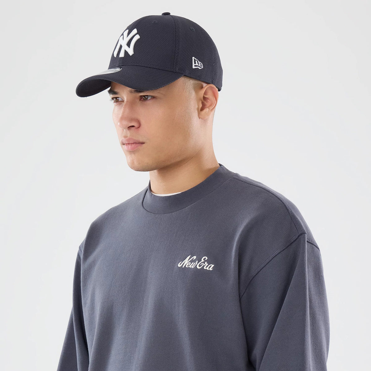 The model is wearing this New Era Open Hem Oversized Crew Neck Sweater in dark grey. 6