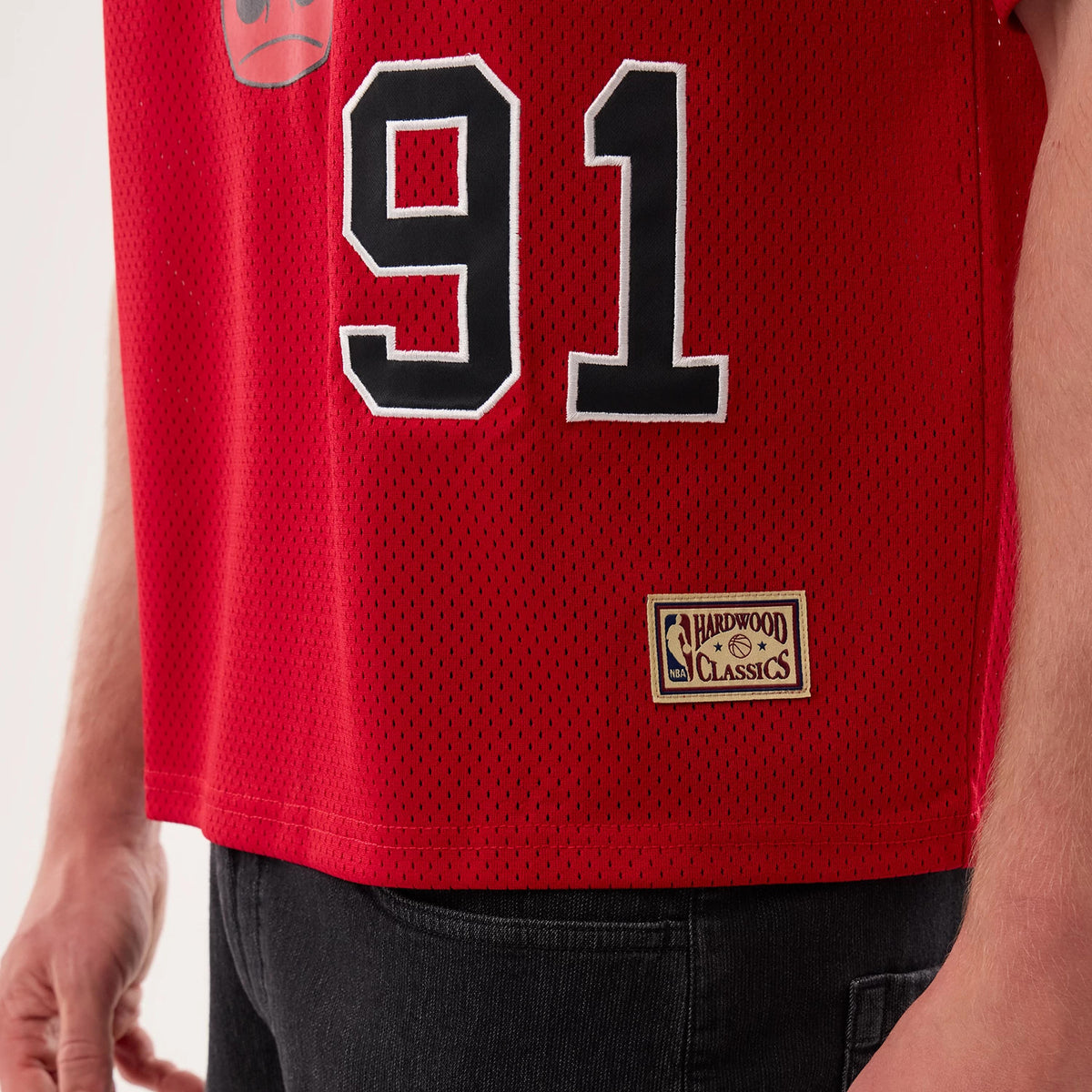 New Era Chicago Bulls NBA Hardwood Classic Mesh Oversized Red T-Shirt, side view on a model displaying the large black and white number 91 on the red mesh fabric, a Chicago Bulls logo above, and a sewn-on Hardwood Classics label near the hem.