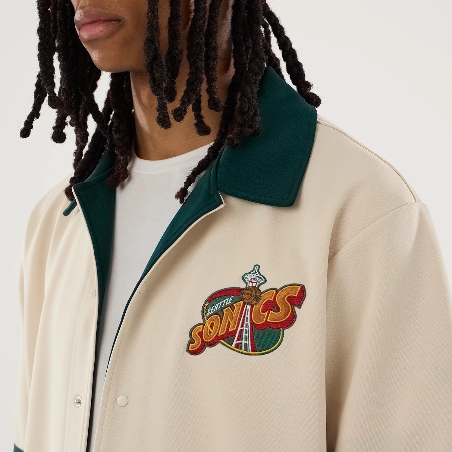 The model is wearing this NBA Hardwood Classic Revere Seattle Supersonics Short Sleeve Shirt in light beige. 5