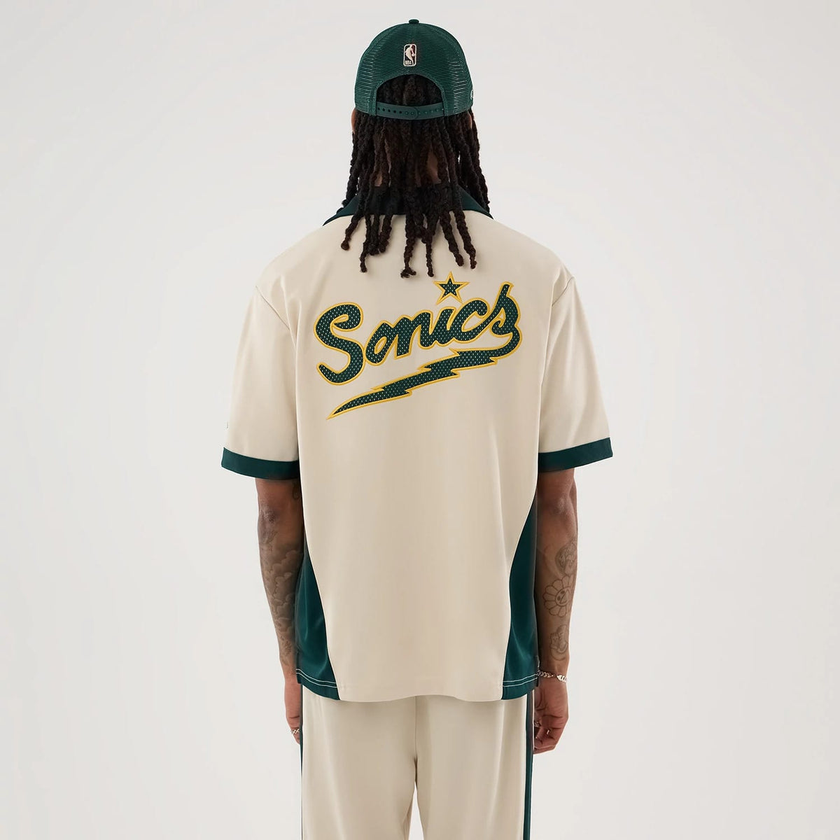 The model is wearing this NBA Hardwood Classic Revere Seattle Supersonics Short Sleeve Shirt in light beige. 2