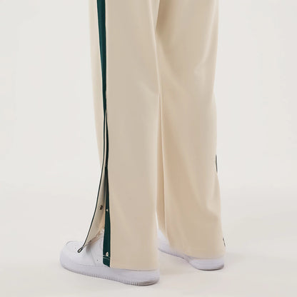 New Era Supersonics NBA Hardwood Classic Beige Straight Leg Joggers, rear view showing the beige fabric with straight-leg cut, dark green side stripes with silver buttons along the legs, worn with white trainers.
