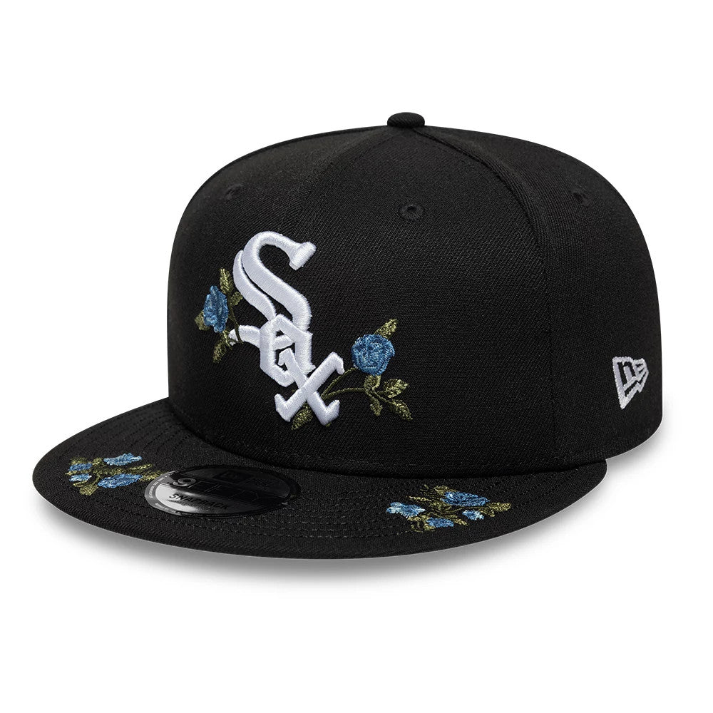 Chicago White Sox MLB Floral Black New Era 9FIFTY Snapback Adjustable Cap, three-quarter view showing a raised white embroidered Sox logo flanked by blue floral embroidery on the front panels and visor, with New Era flag logo on the left side.