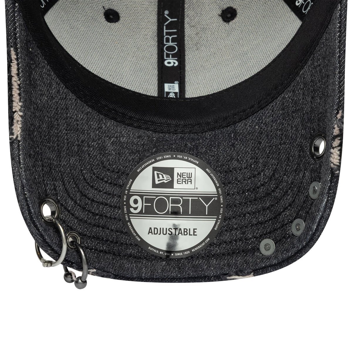New Era Hardware Washed Black 9FORTY Adjustable Cap, inside view showing black taping with repeated 9FORTY branding, a silver 9FORTY size sticker on the washed black curved visor, and eyelets near the cap's front edge.