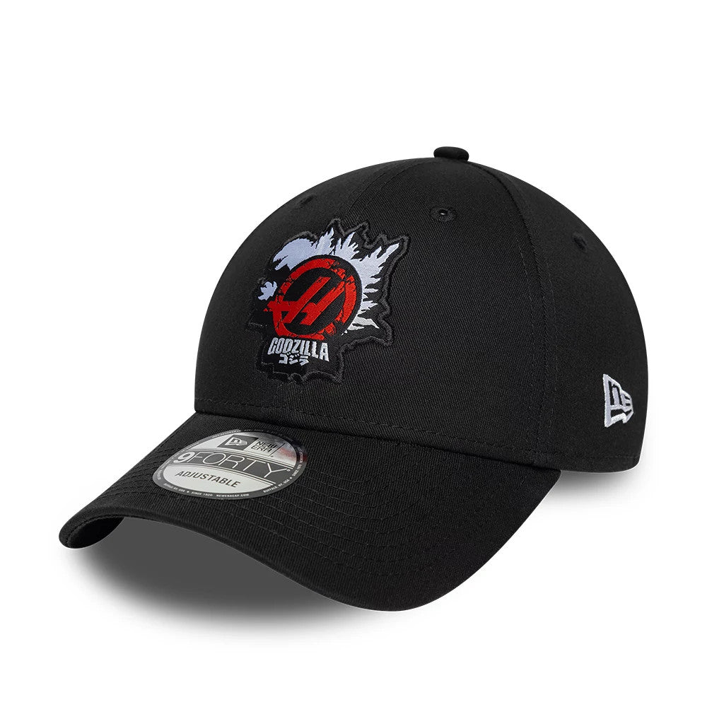 Godzilla X TGR Haas F1 Black New Era 9FORTY Adjustable Cap, front view showing a white and red embroidered logo on the front panel, a curved black visor with a 9FORTY size sticker, and a white New Era flag logo on the left side.