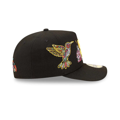 San Diego Padres MLB Day Of The Dead Black New Era 59FIFTY A-Frame Fitted Cap, side view showing a colourful embroidered hummingbird and sugar skull on the black crown, with a structured black visor and a 59FIFTY size sticker on top.