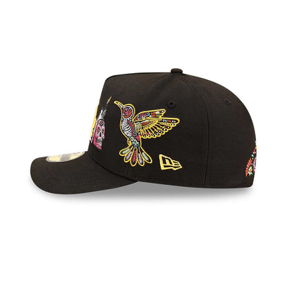 LA Dodgers MLB Day Of The Dead Black New Era 59FIFTY A-Frame Fitted Cap, side view showing a colourful embroidered hummingbird on the side panel, the yellow New Era flag logo, and the flat black visor with a gold 59FIFTY size sticker.