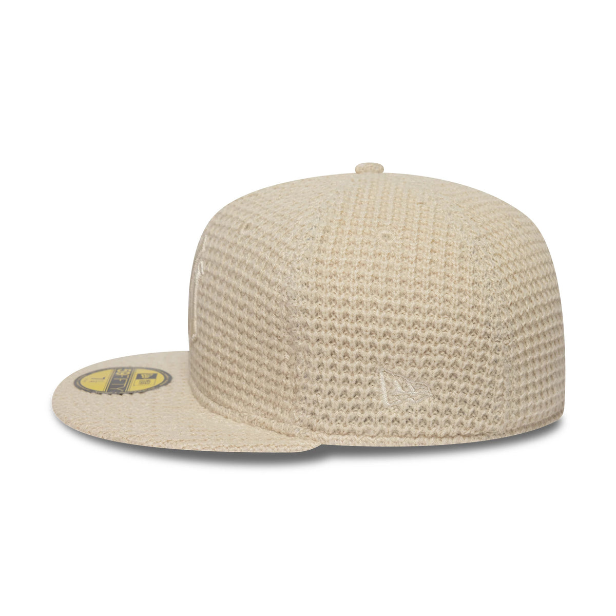 New York Yankees MLB Knitted Light Beige New Era 59FIFTY Fitted Cap, side view showing the New Era flag logo embroidery on the textured beige crown, beige visor with a gold 59FIFTY size sticker, and matching top button.