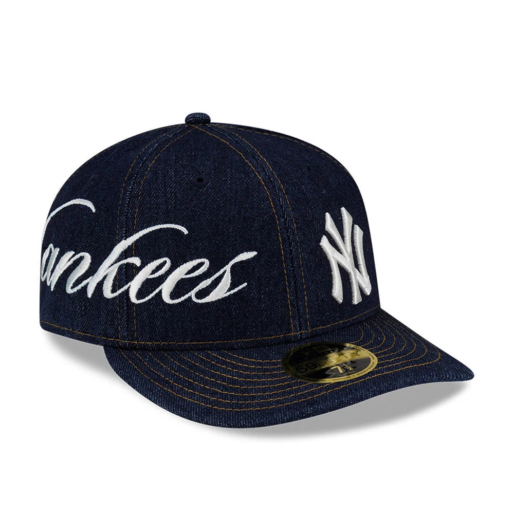 New York Yankees MLB Denim Navy Low Profile New Era 59FIFTY Fitted Cap, three-quarter view showing the white Yankees script embroidered on the front panel, the NY logo on the side, and the gold 59FIFTY size sticker on the navy curved visor.