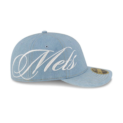 New York Mets MLB Denim Pastel Blue New Era Low Profile 59FIFTY Fitted Cap, three-quarter view showing the white embroidered script Mets across the front, a gold 59FIFTY size sticker on the visor, and eyelets on the structured denim crown.
