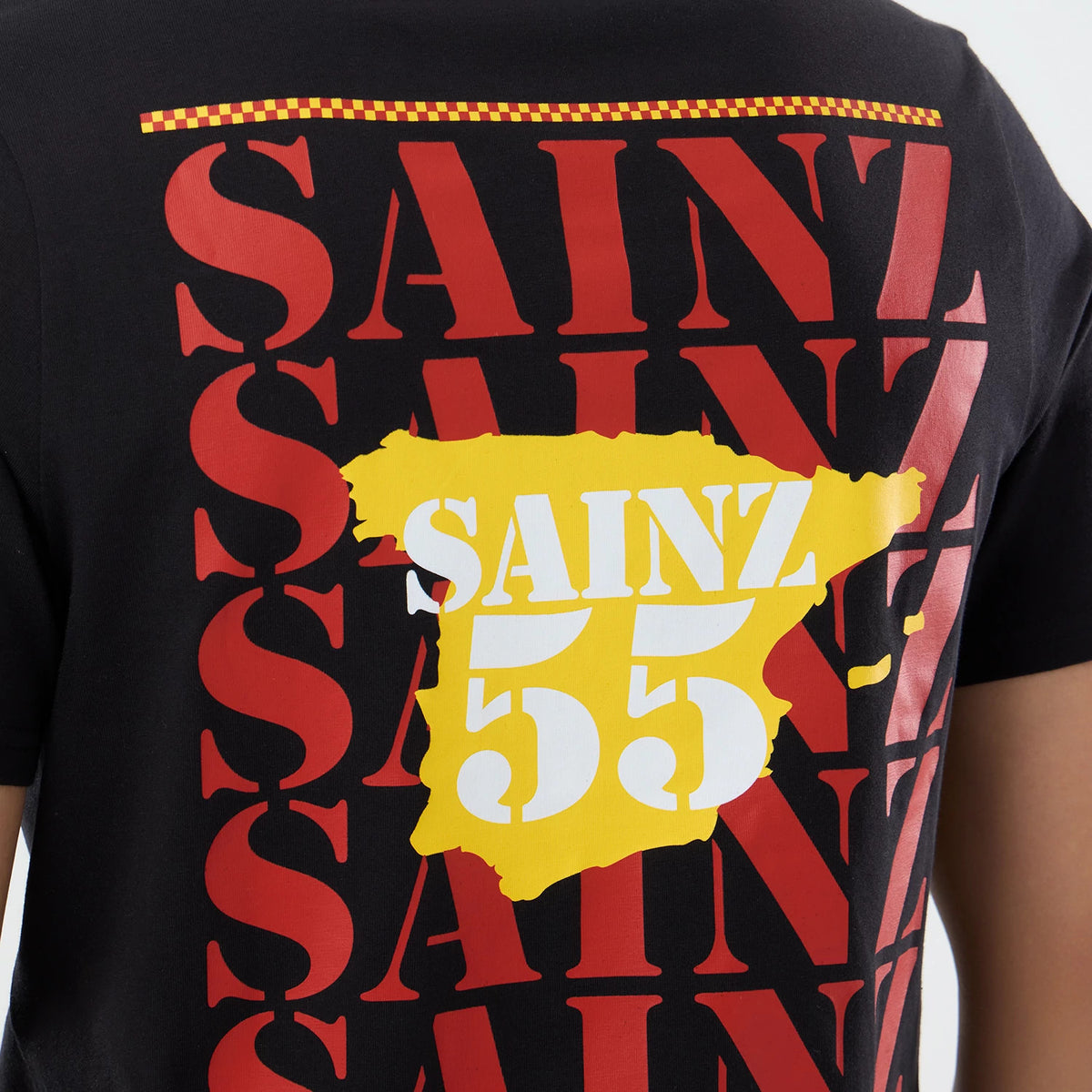 New Era Williams Carlos Sainz Spain Race Special Black T-Shirt, back view displaying large red SAINZ text in multiple layers, with a yellow Spain map graphic overlaid featuring white SAINZ 55 lettering and a red and yellow chequered stripe above.