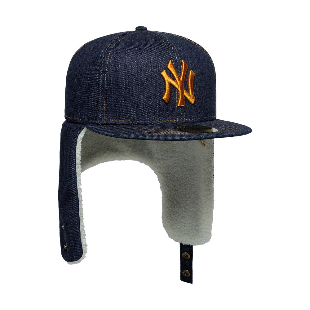 New York Yankees MLB Denim Navy Dogear New Era 59FIFTY Fitted Cap, three-quarter view showing the gold NY logo in raised embroidery on the front panel, a flat denim visor with a 59FIFTY size sticker, and fleece-lined ear covers with button straps.