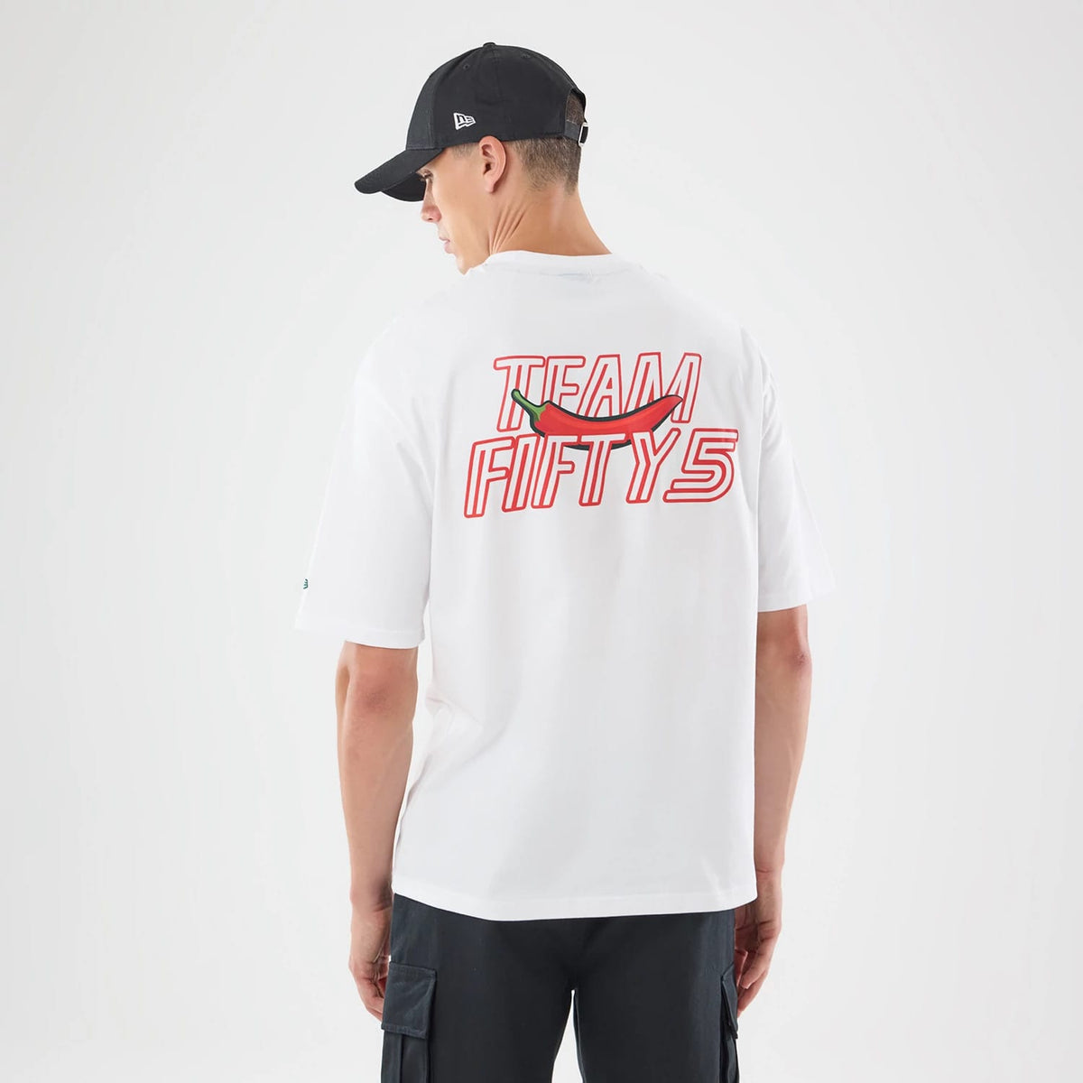 The model is wearing this Carlos Sainz Team Fifty5 Mexico Oversized T-Shirt in white. 2