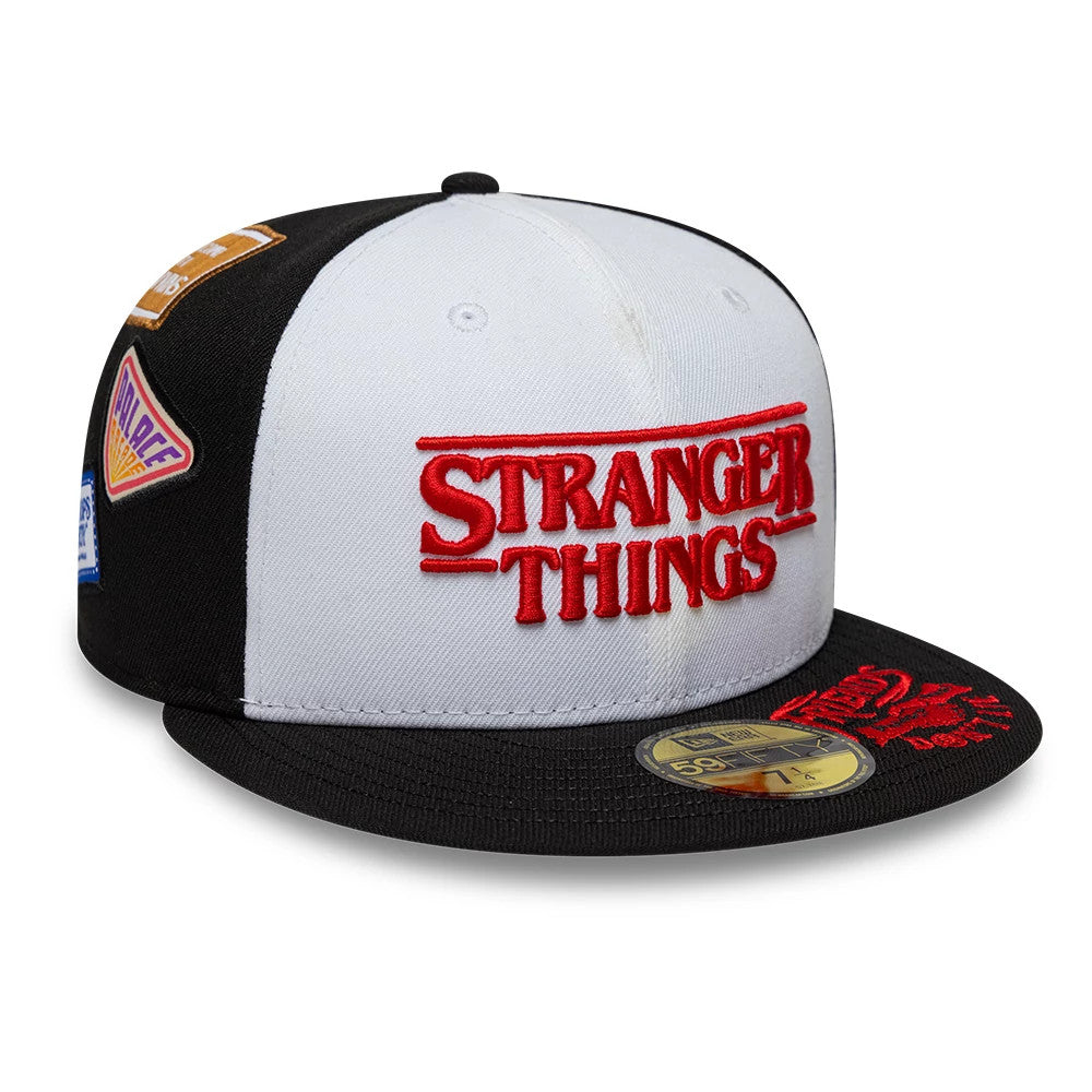 Netflix Stranger Things 10 Years Black New Era 59FIFTY Fitted Cap, three-quarter view showing the red embroidered Stranger Things logo on the white front panel, with additional patches on the side and a gold 59FIFTY size sticker on the black visor.