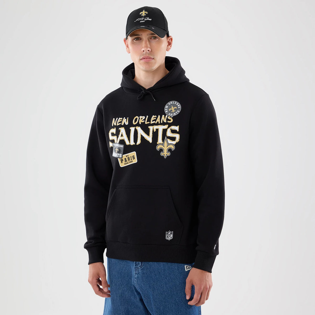New Era New Orleans Saints NFL Patch Black Pullover Hoodie, front view on-model highlighting the embroidered New Orleans Saints logo and lettering across the chest, an additional patch and logo near the pocket, styled with a matching black cap.