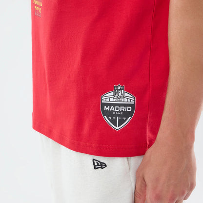 New Era Atlanta Falcons NFL Graphic Slogan Red Oversized T-Shirt, side view showing the prominent black and white printed NFL Madrid Game logo near the hem, a yellow Atlanta 2024 slogan on the front, and an embroidered New Era logo on white shorts.