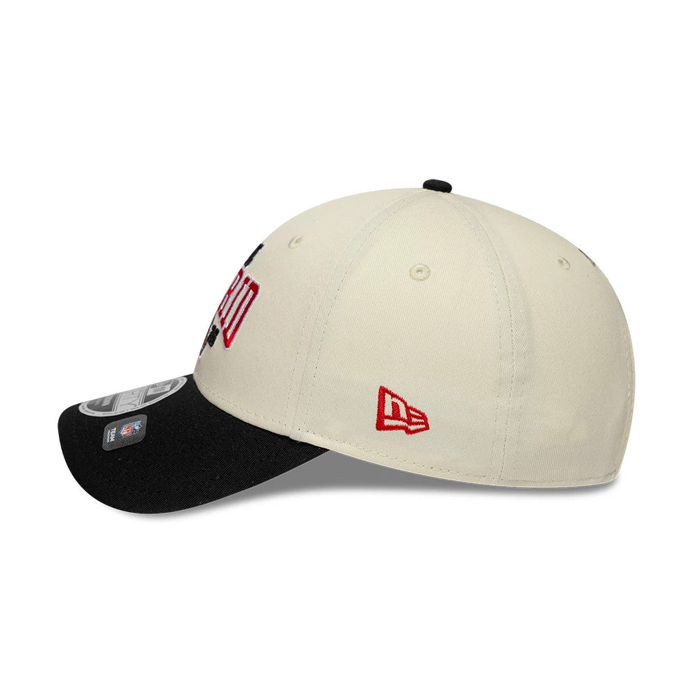 Falcons NFL International Games 2026 Madrid White & Black New Era 9FORTY M-Crown Adjustable Cap, side view showing the red embroidered New Era flag logo on the cream crown, a black visor with stickers, and a curve in the visor.