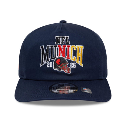 New England Patriots NFL International Games 2026 Munich Dark Blue New Era 19TWENTY Adjustable Cap, front view showing the multicoloured embroidered NFL Munich 2026 graphic on the structured crown, with a 19TWENTY size sticker on the dark blue visor.