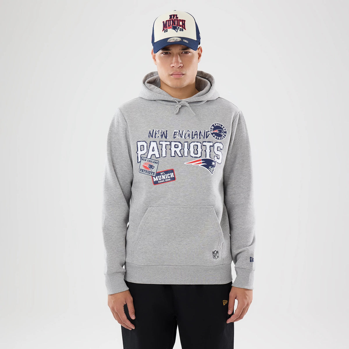 The model is wearing this NFL International Series Games 2026 New England Patriots Pullover Hoodie in grey. 1