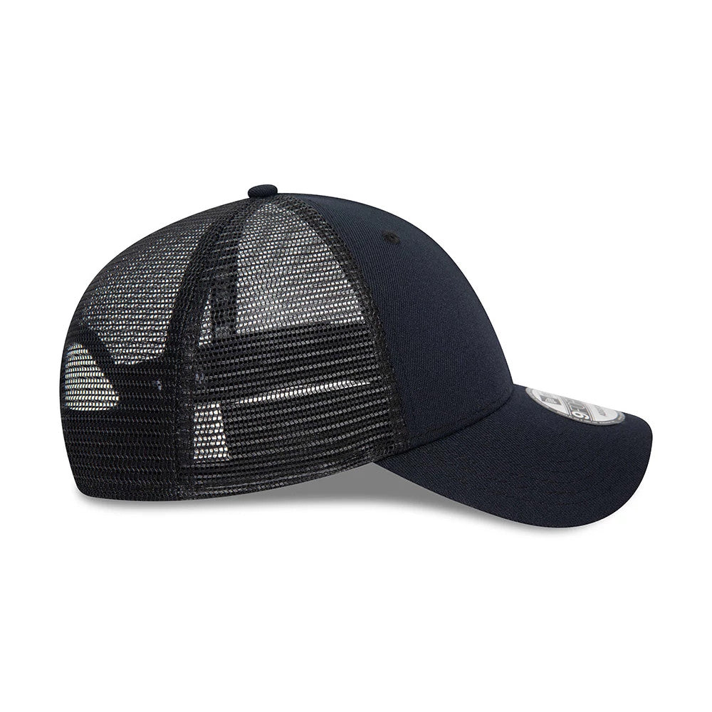 New Era Blank Navy New Era 9FORTY Trucker Cap, side view showing the black mesh back panels extending to the structured navy front, with the curved visor and attached 9FORTY size sticker above the visor.