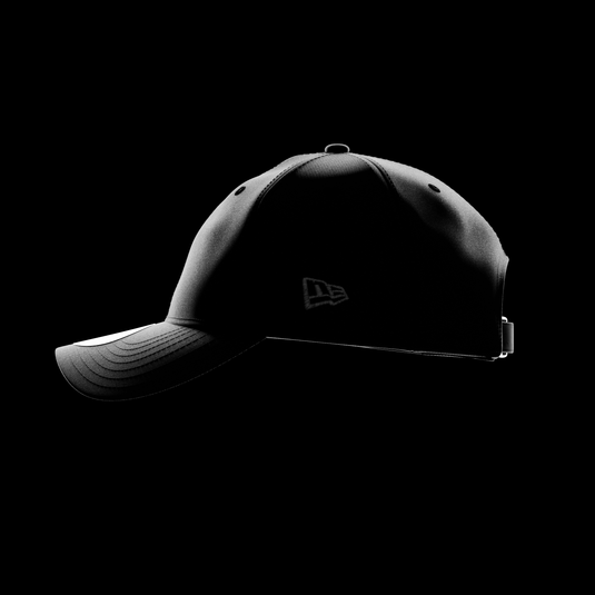 A black 9TWENTY cap shown in side profile against a solid black background, featuring a subtle tonal New Era Flag on the side and a structured curved brim.