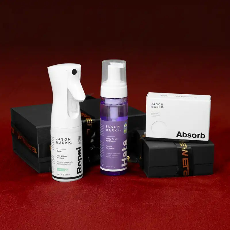 Blue baseball cap with white logo, cleaning cloth, and spray bottle on a reflective surface.